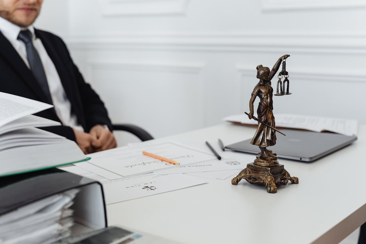 A legal professional's workspace featuring Lady Justice statue, documents, and a laptop.